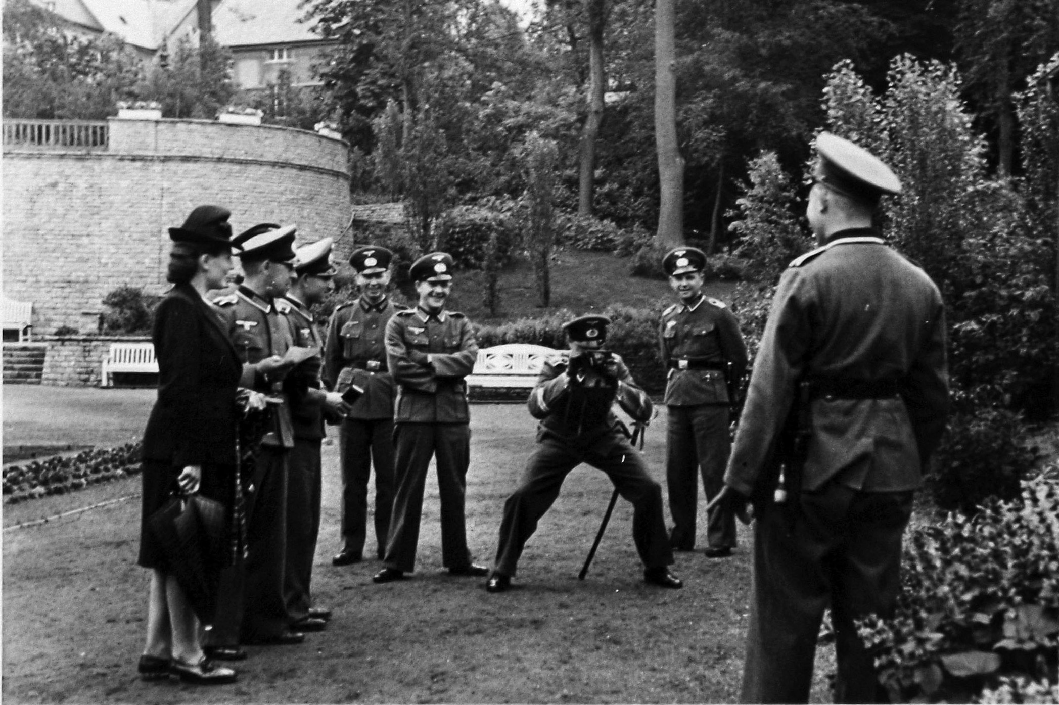 Important occasion? Although the identity of the subject is unknown because his back is toward the viewer, this German soldier is the object of attention for a photographer and an entourage of smiling friends. The formal garden setting and the dressed-up woman suggest this might have been a wedding photo and the man is the groom. 