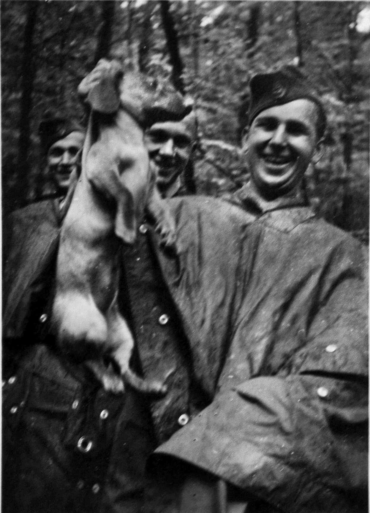 A soldier in a rain cape and his comrades enjoy a photo op with a Daschund who might not share their enthusiasm. Mascots were often found with field units, the animals serving to bring some emotional warmth to the brutal work at hand.