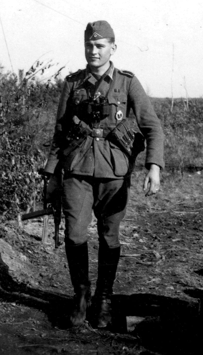 Lubbeck, a private first class and forward observer for his company’s howitzers in 1942, walks the front lines with an MP-40. He is wearing the infantry assault badge and has the ribbon denoting the Iron Cross in his buttonhole.