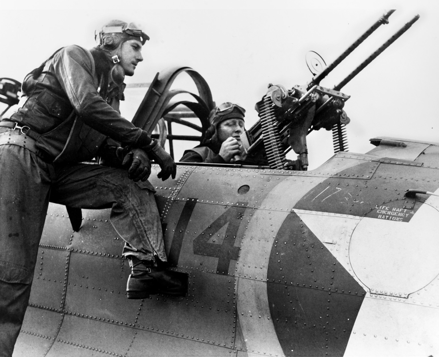 Lieutenant (jg) Woodie L. McVay Jr. watches as radio-gunner K. W. Jobe tests the rear-facing, .30-caliber machine-gun system on their SBD-3 Dauntless dive bomber during Operation Torch.