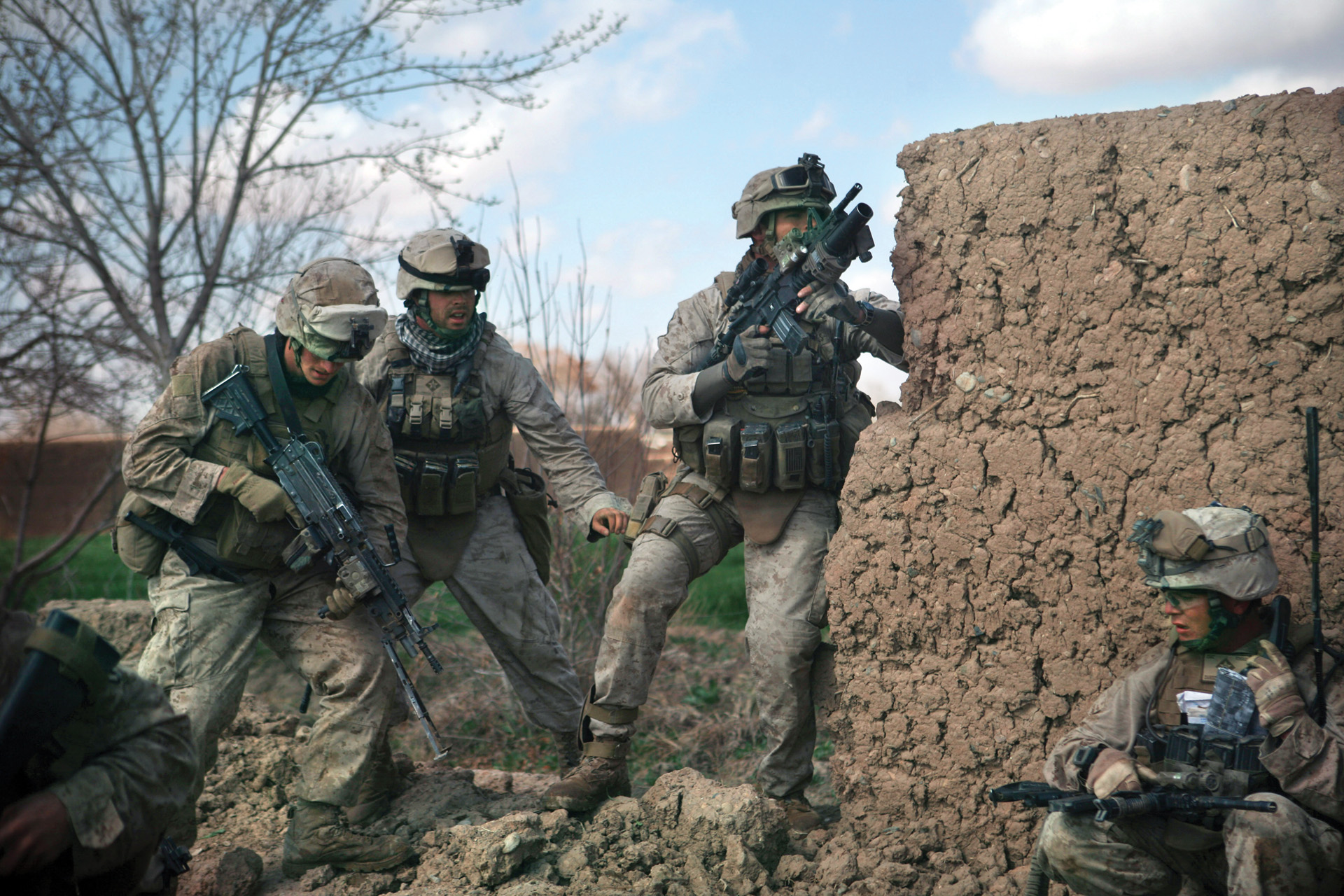 Marines take cover behind a mud-brick wall like the one in South Ganjal village where three Marines and a Navy corpsman became pinned down when the Taliban sprang their dawn ambush. 