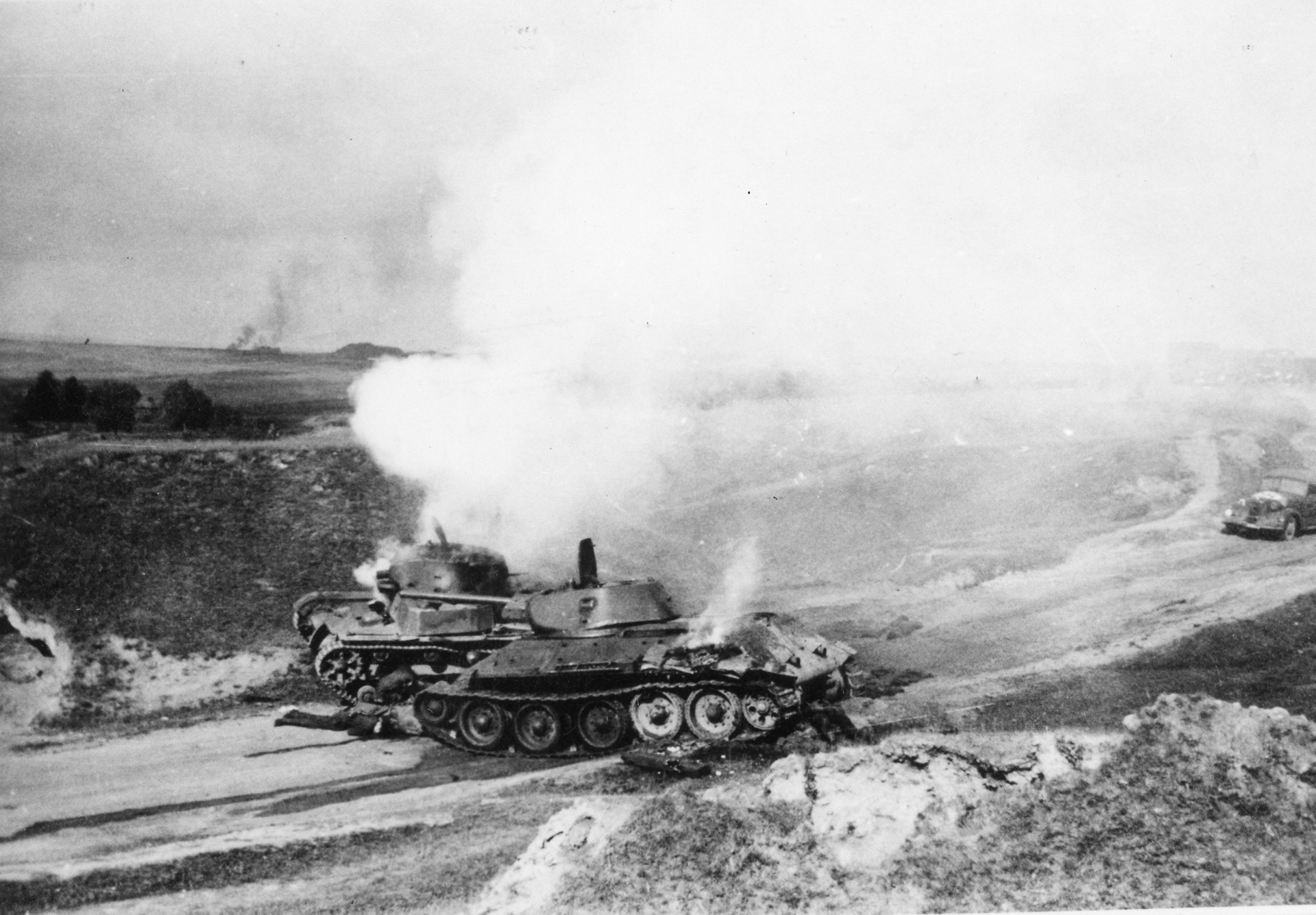 A Soviet T-34 tank (foreground) and another unidentified armored vehicle smolder after being hit by German antitank fire. As a forward observer, Lubbeck managed to stop an armored attack by directing a 150mm artillery piece to knock out two tanks.