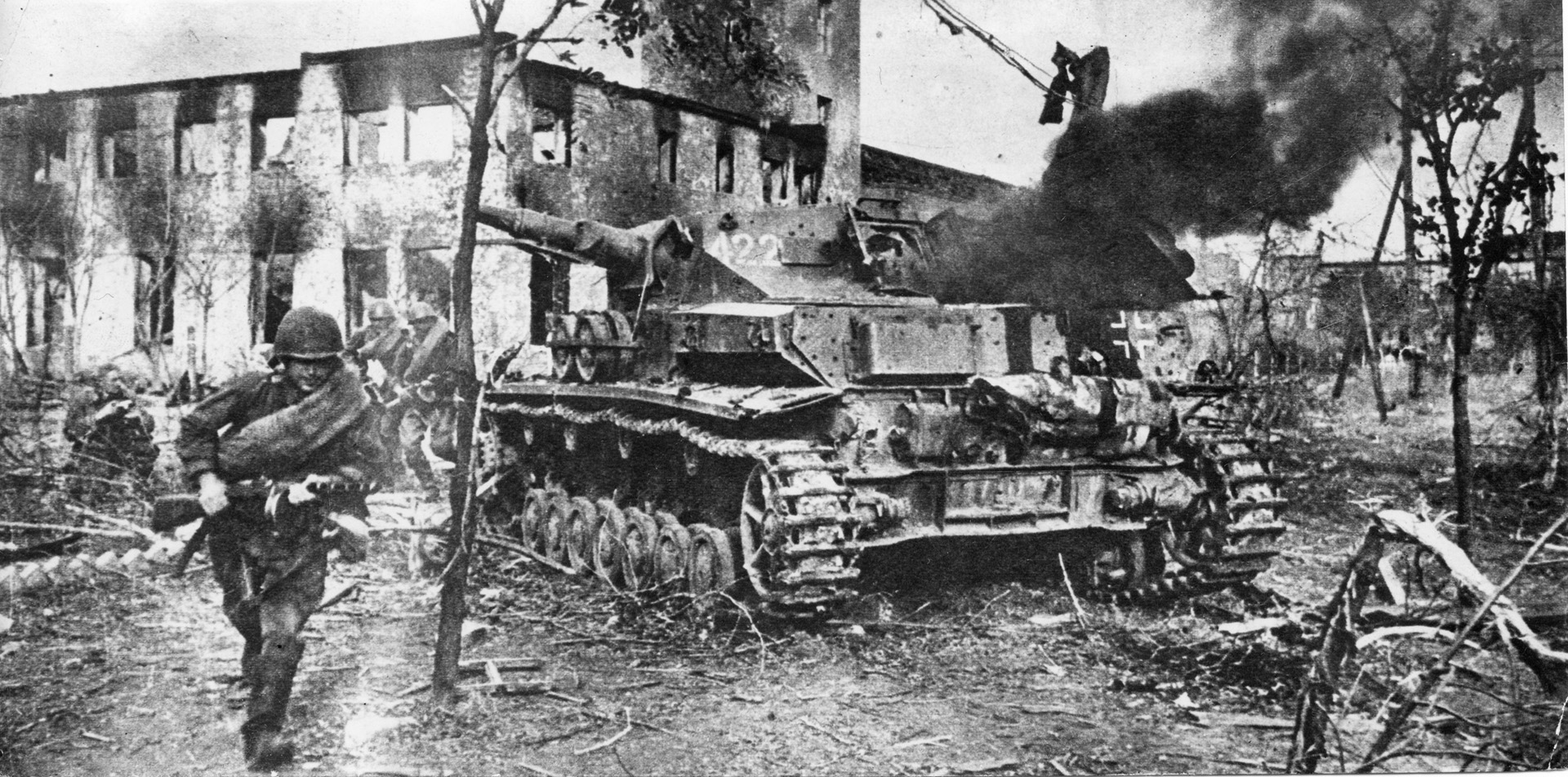 A Red Army soldier, with his comrades behind him, dashes past a knocked-out German Panzer IV during the German retreat from the Soviet Union. Casualties on both sides during the war were horrendous.