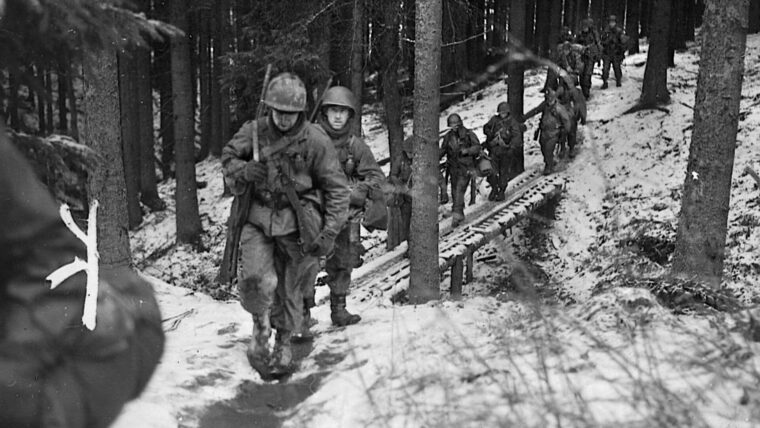A platoon of the green U.S. 106th Infantry Division trudges through a Belgian woodland. Although they were told that they would occupy a quiet sector of the Western Front in December 1944, the Golden Lions were soon in the teeth of the Battle of the Bulge.