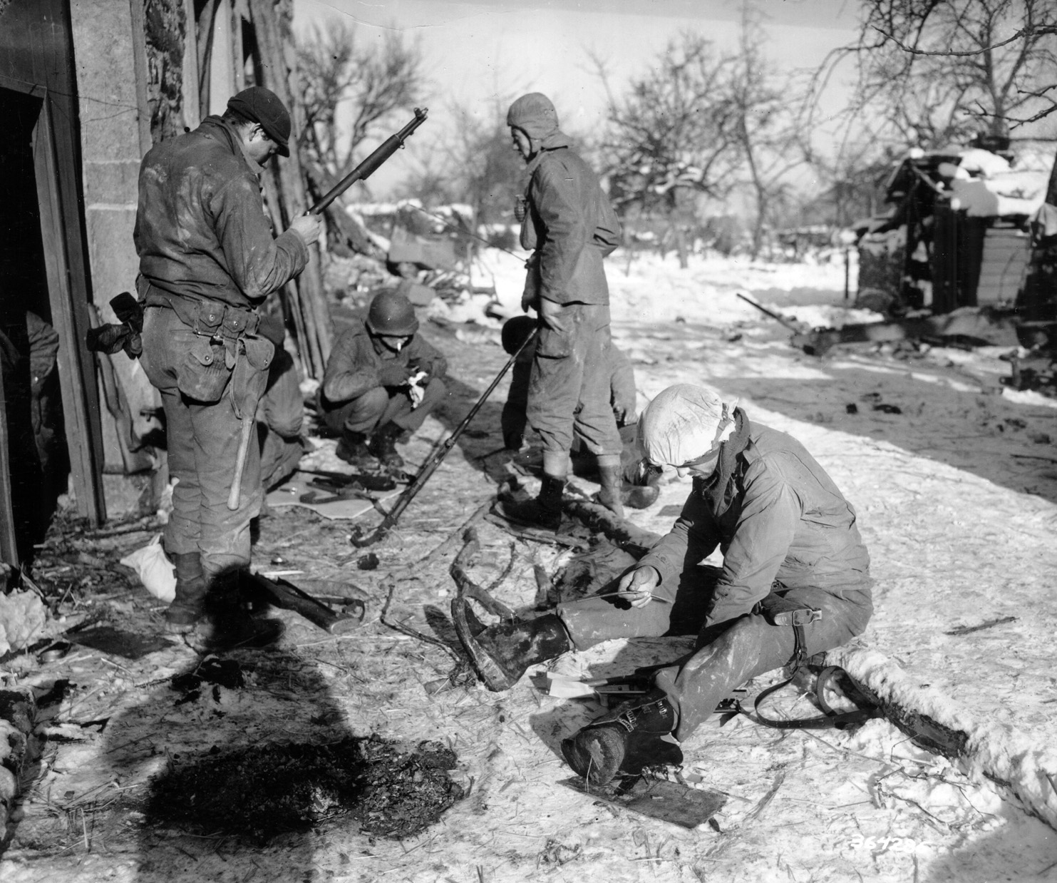 Soldiers of the 424th Infantry Regiment take a moment to clean their weapons during a lull in the fighting near the village of Wanne, Belgium. 