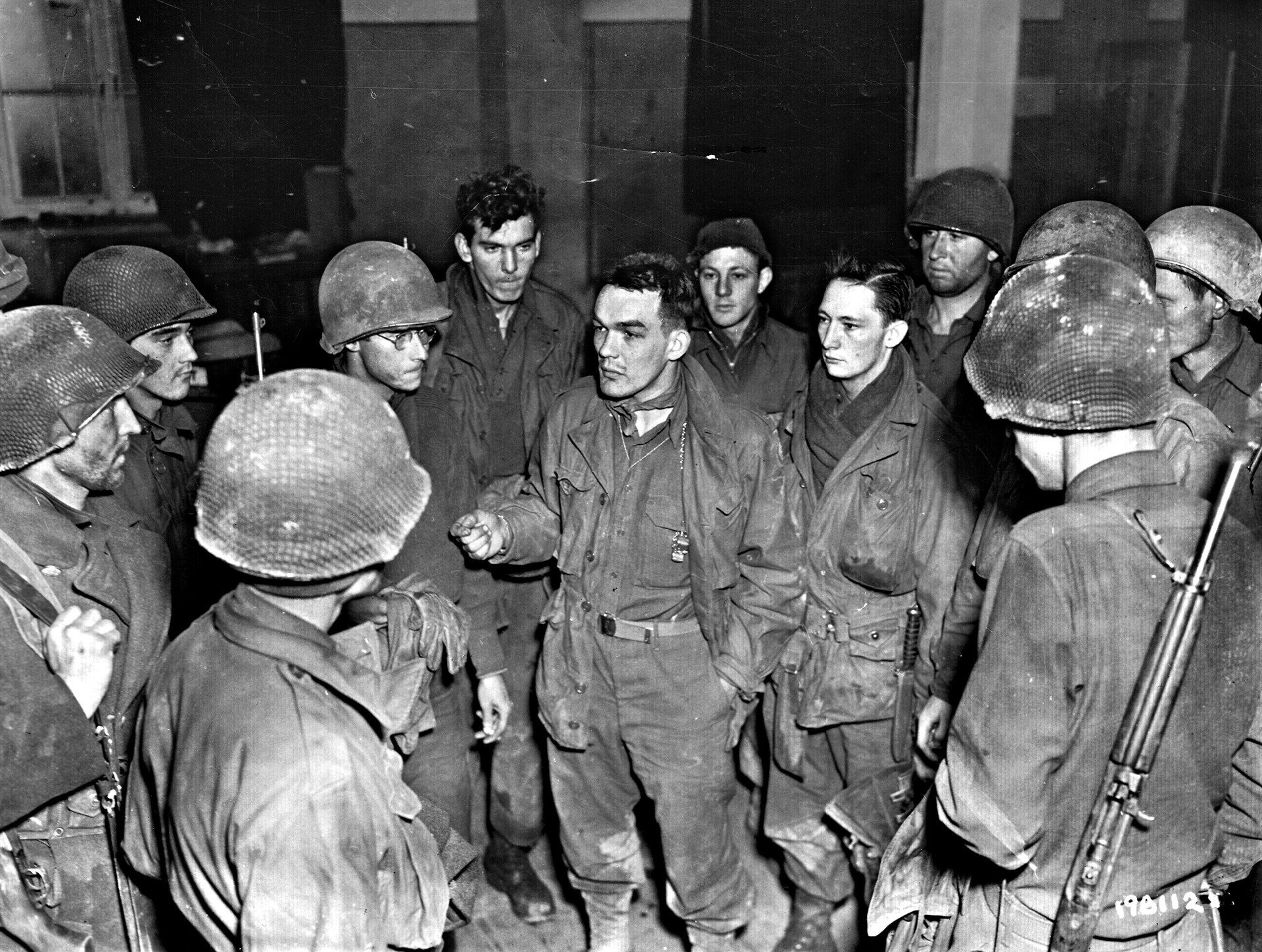 Lieutenant Ivan Long, center, talks with members of his Intelligence and Reconnaissance Platoon, 423rd Infantry Regiment. These soldiers were among the few who escaped the the advancing Germans on the Schnee Eifel, making their way to American lines around St. Vith.