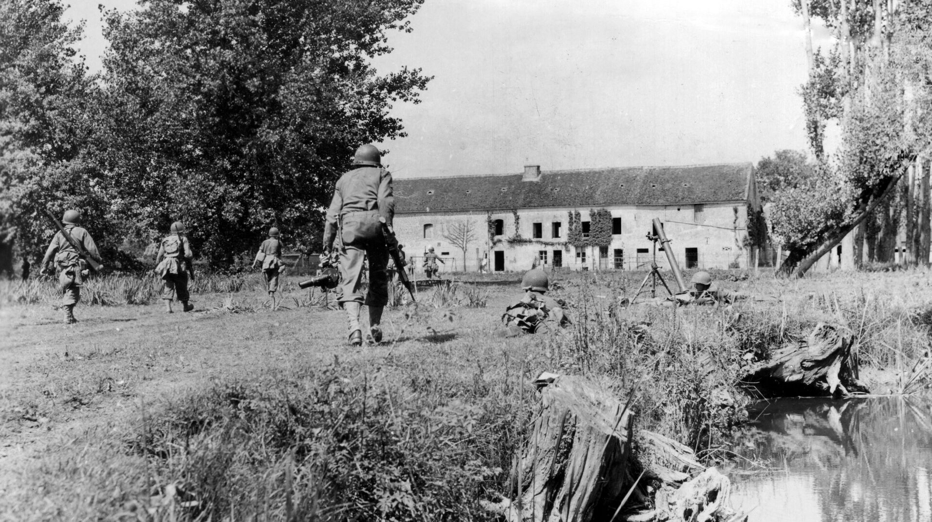 An infantry patrol of the 318th Regiment, 80th Division, moves forward against an enemy-occupied farmhouse near Argentan as the supporting mortar section waits to provide heavier fire if needed.