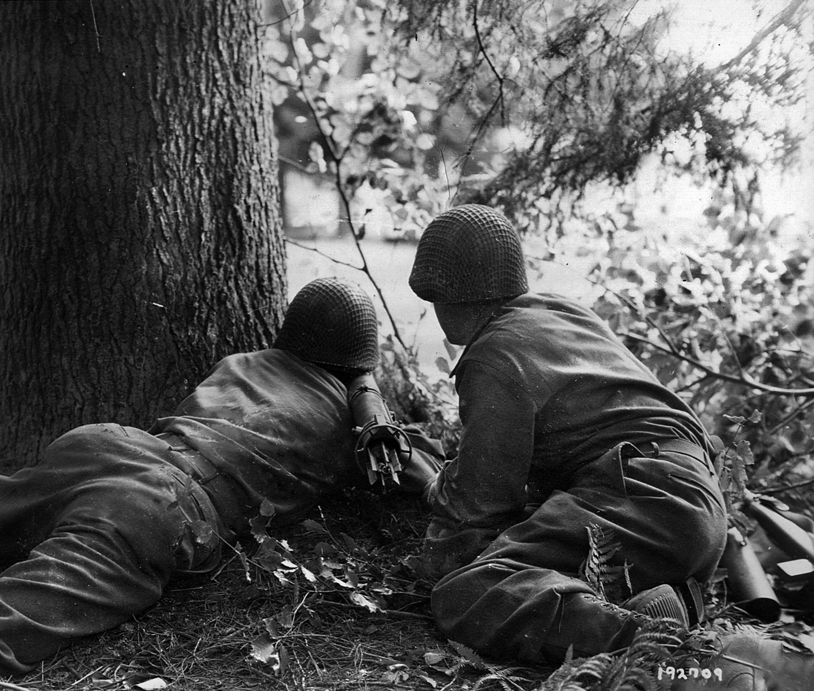An American bazooka team intent on destroying an oncoming German halftrack peers from cover during action at the Falaise Pocket.