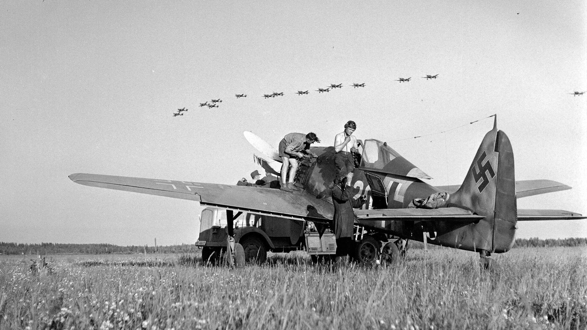 An Fw-190 of JG-52 is serviced at an airfield in Immola, Finland, while Junkers Ju-87 Stuka dive bombers fly in the distance.In the summer of 1944, Nazi Germany deployed Fw-190 fighters to Finland to assist their allies in the fighting against the Soviet Union.