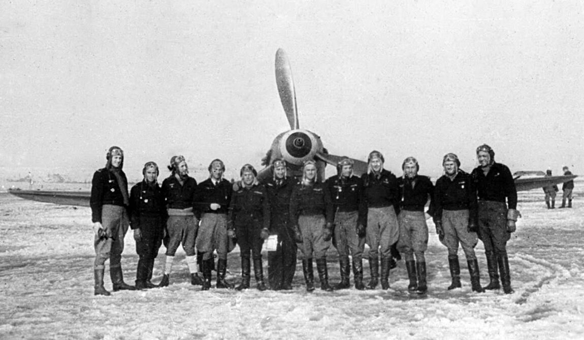 Pilots of the Normandie Niemen, some of them wearing decorations, pause for the camera in front of one of their fighter planes on the Eastern Front.  