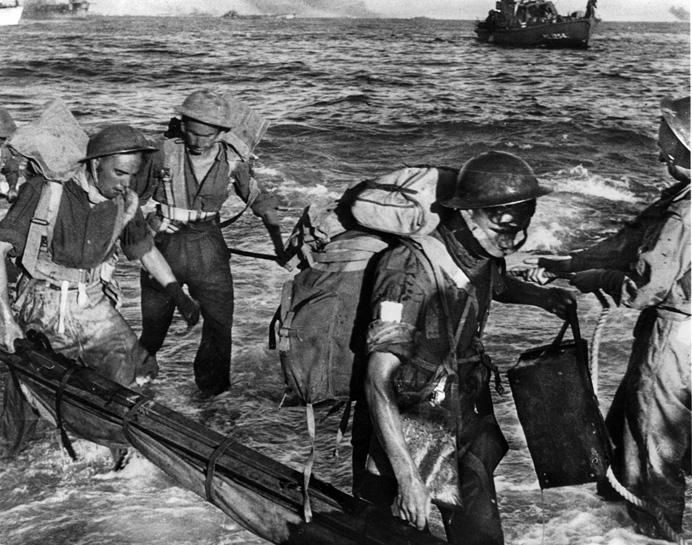 British troops come ashore in southern Sicily with the help of a rope to get through the heavy surf.