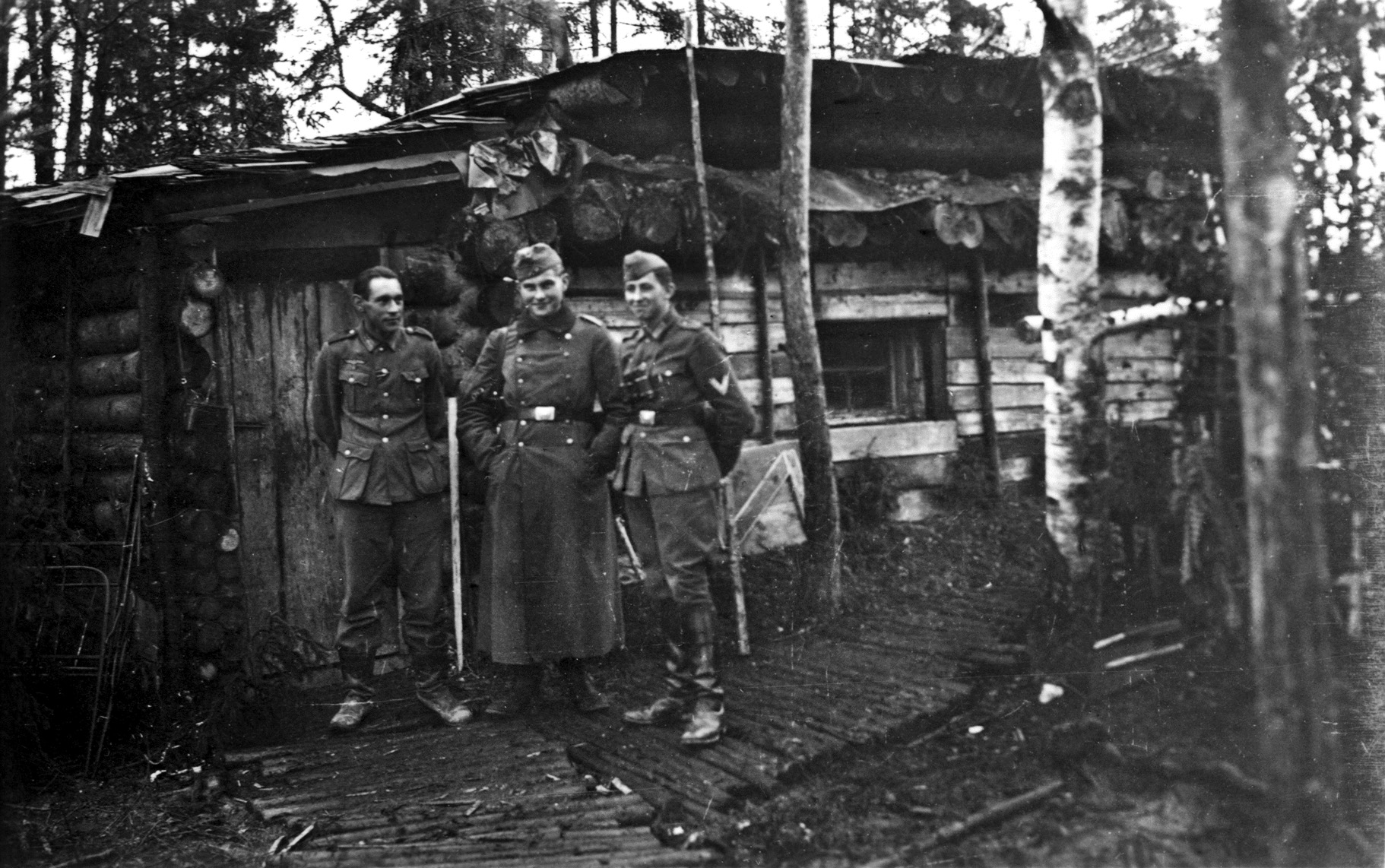 The author poses between two comrades outside a wooden bunker in a forest at Oranienbaum, located on the Gulf of Finland west of St. Petersburg (then Leningrad) in the summer of 1942.