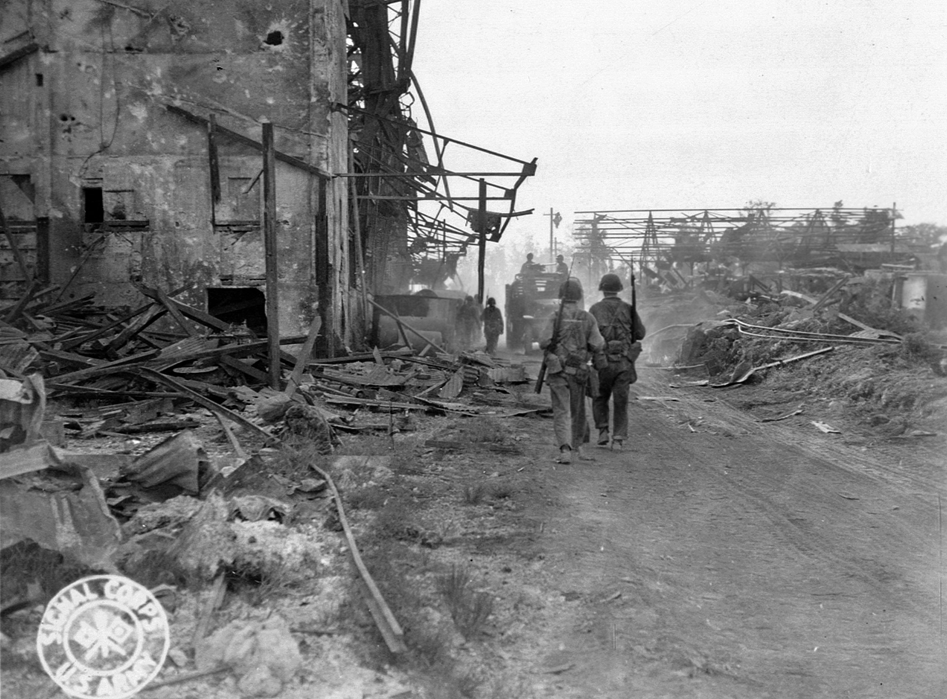 Soldiers and vehicles advance through a destroyed section of Saipan village, the island’s capital and largest town. Sporadic resistance continued until November 1944.