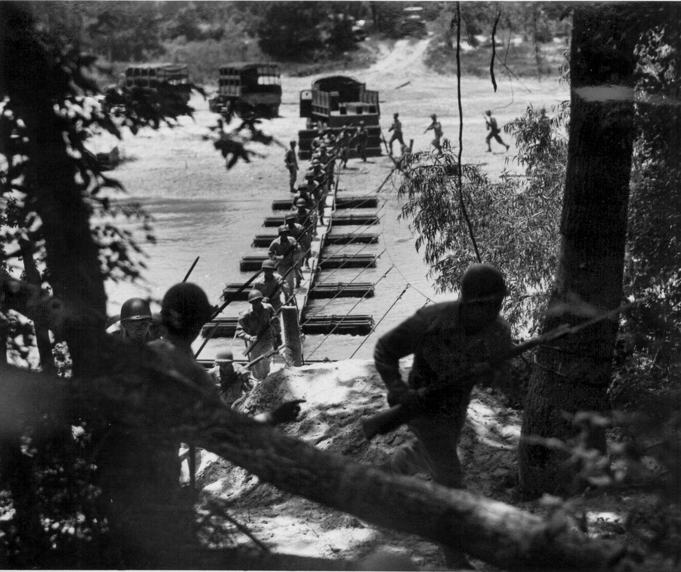 Members of the 442nd RCT rush across a pontoon bridge built by the 232nd Engineer Company at Camp Shelby, July 1943.