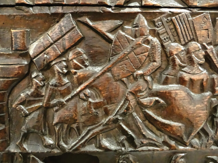 Flemish foot soldiers block the charge of a French knight by attacking both horse and rider. A pike is thrust at the knight’s head while a sword is driven into the horse’s chest. 