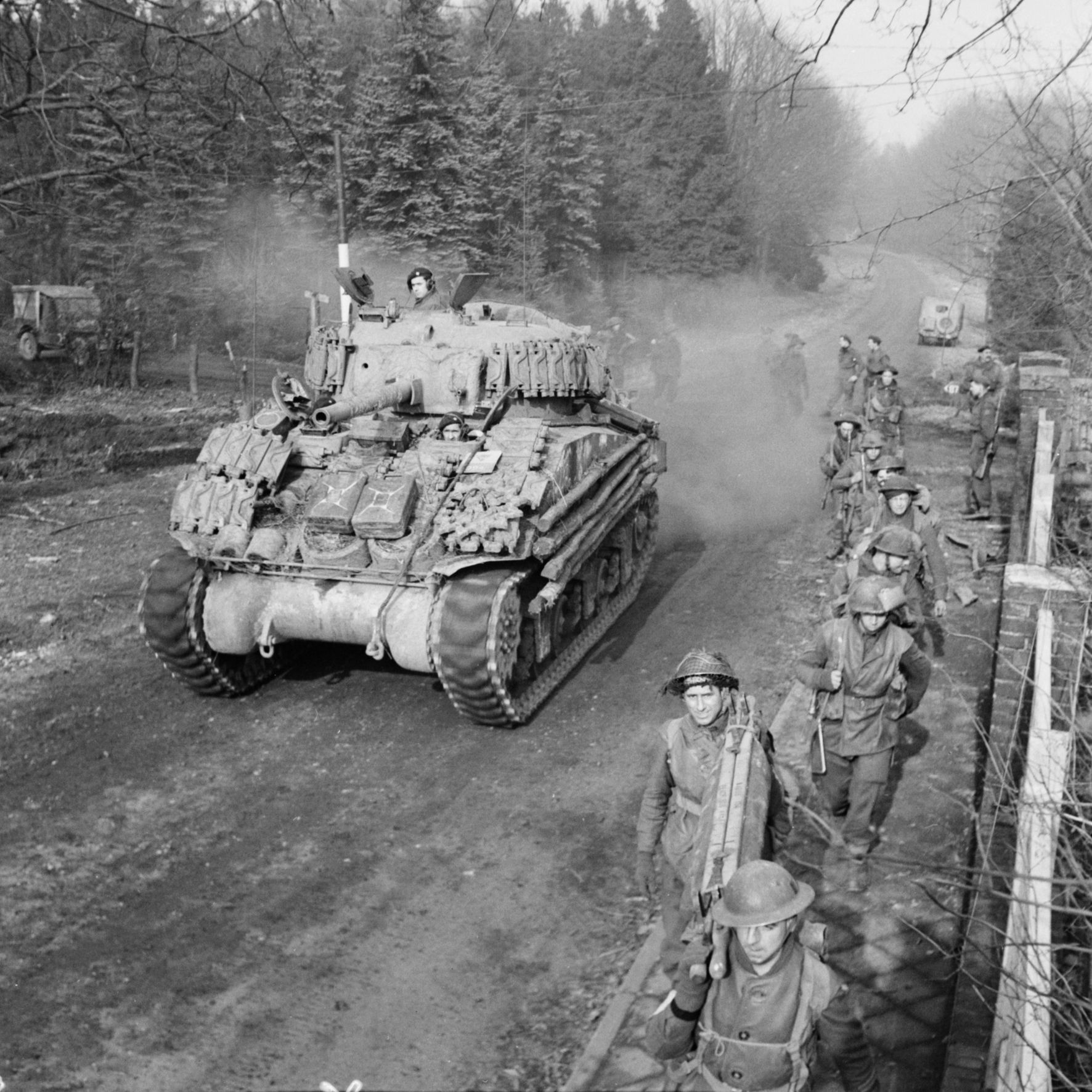 A Sherman tank rolls past soldiers of the British 43rd Wessex Division on February 17, 1945. This photograph was taken during the Allied advance on the German town of Goch as fighting raged in the Reichswald. 