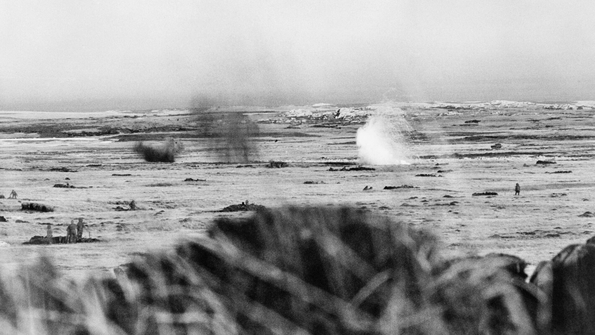 British forces used folds in the landscape for cover in the bleak terrain during the attack on Port Stanley. Here soldiers of the 2nd Battalion of the Scots Guards take cover below Goat Ridge as an Argentine shell ignites a British phosphorous grenade. 