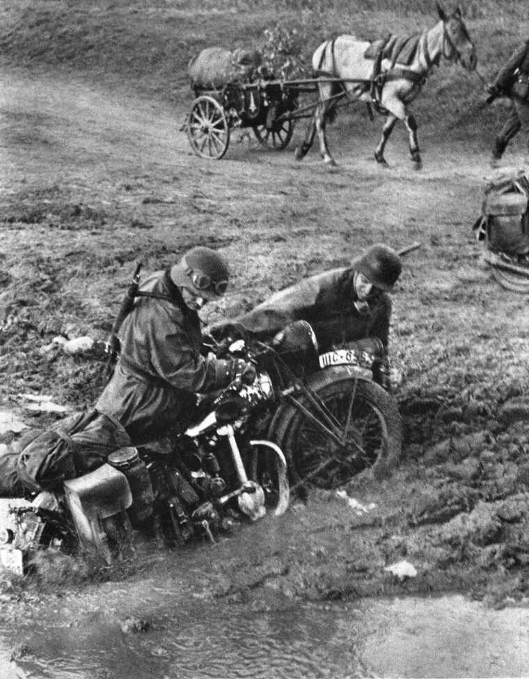 Two German soldiers try to pull their motorcycle from a muddy stream during the march on Moscow.