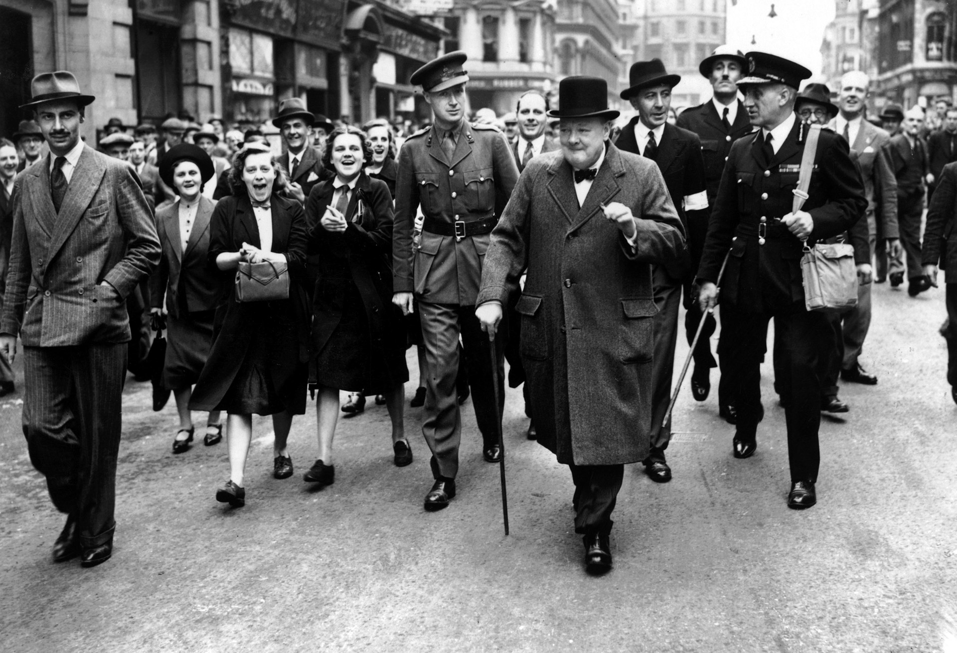 Prime Minister Winston Churchill, cheered on by his supporters, walks through East End streets in September 1940, to inspect damage and give Londoners “heart.”