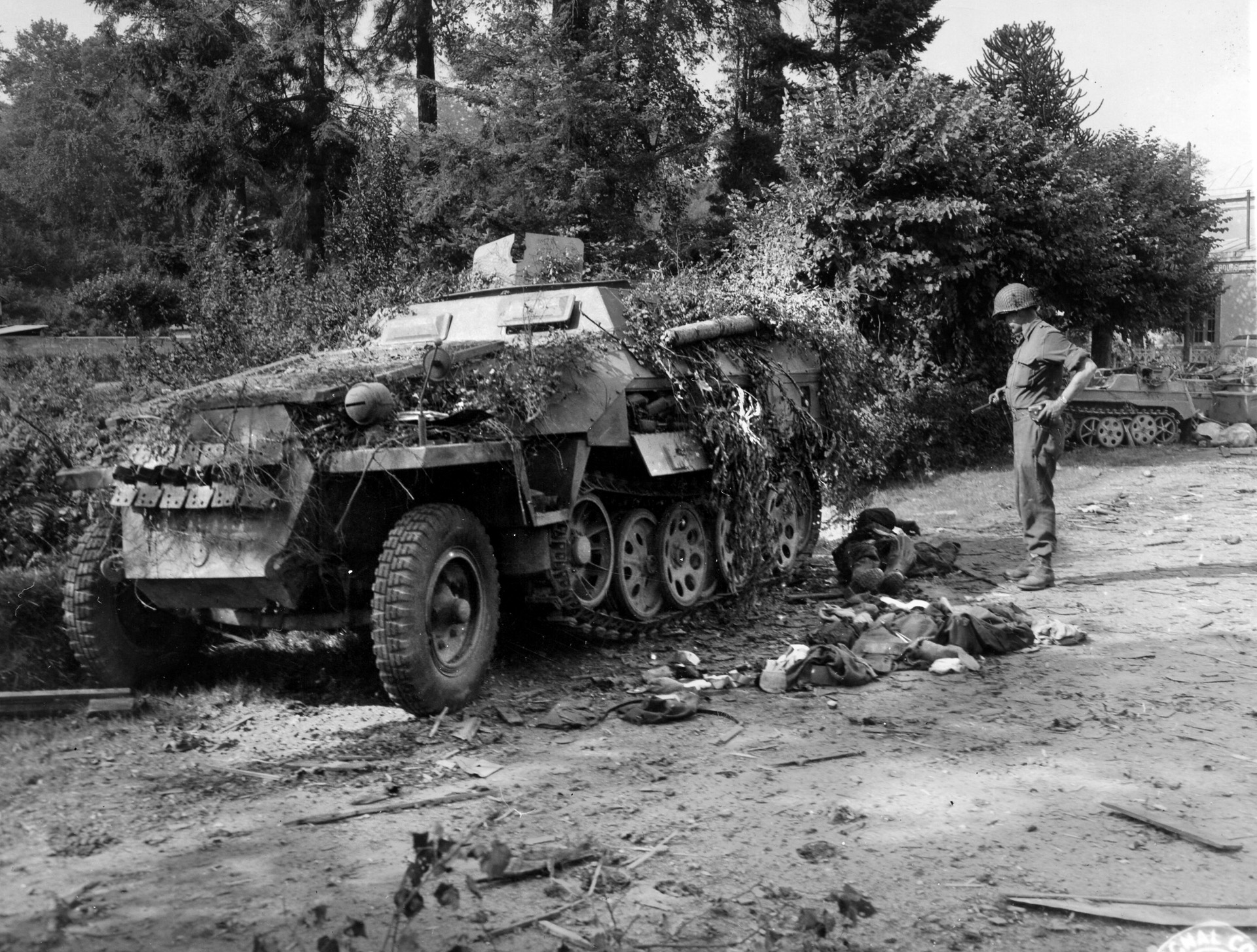 An American officer examines dead enemy soldiers lying beside a German halftrack destroyed during the attack on Mortain. Although American casualties were high, the Germans suffered even more.