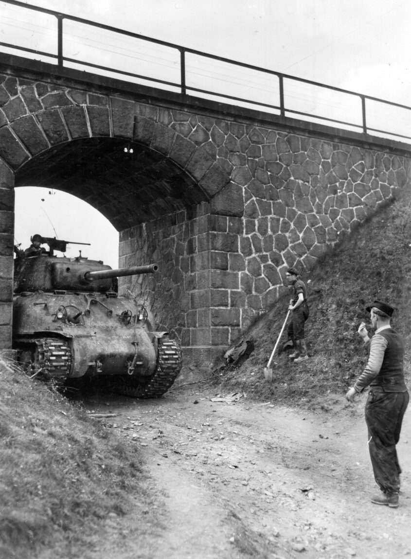 A Czech civilian with shovel (right) watches as an M4 Sherman tank of the 782nd Tank Battalion, attached to the 97th Infantry Division, moves cautiously through an underpass. The retreating Germans had blown a bridge during the U.S. Army’s liberation of Cheb, Czechoslovakia, in April 1945. Attaching a tank battalion to an infantry division gave the foot soldiers the armored punch they needed.
