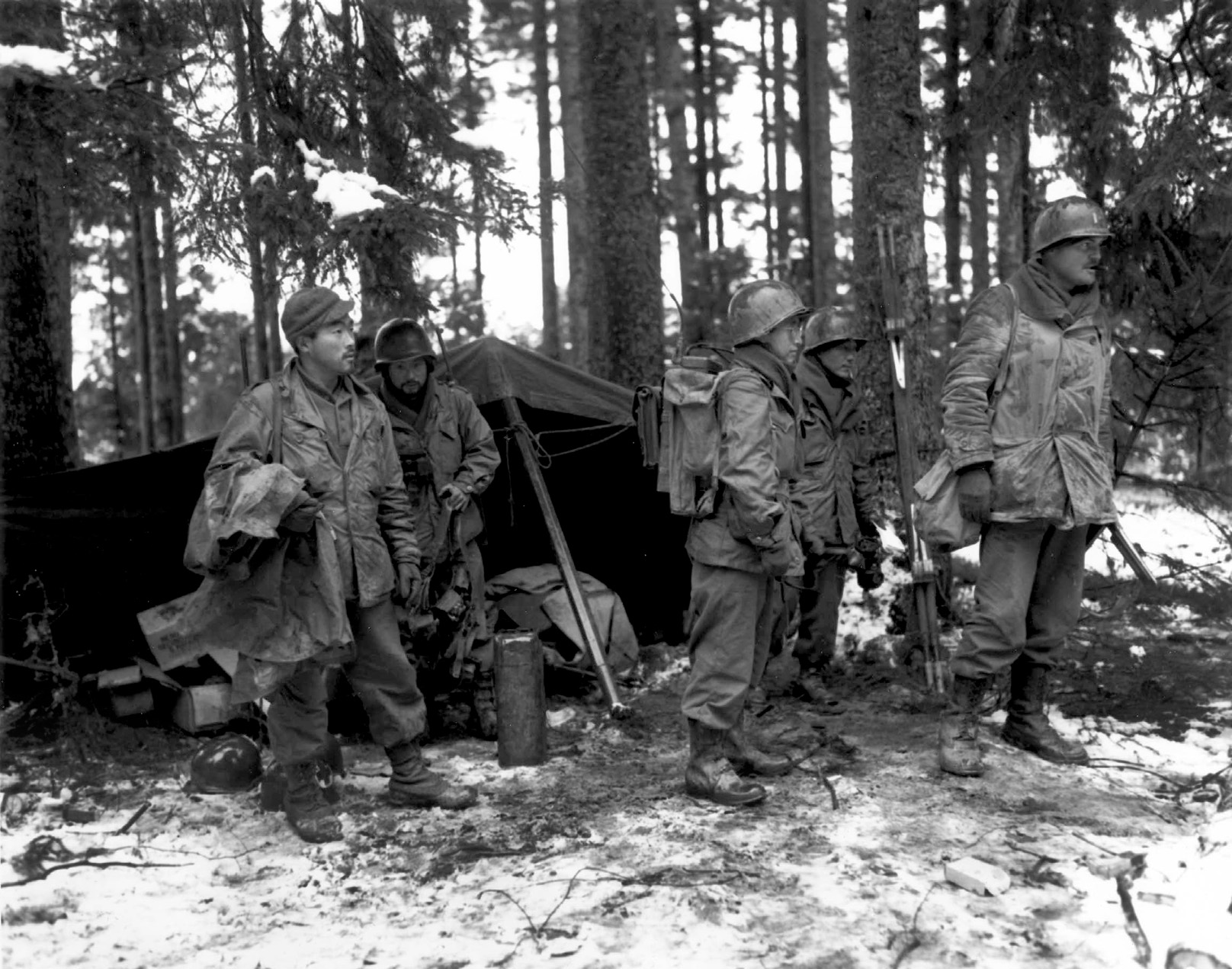 After spending a cold, wet, and miserable night in the woods near St. Die, France, members of Company F, 2nd Battalion, 442nd RCT prepare to move out of their command post with their lieutenant, Joseph W. Hill (right), November 13, 1944. 