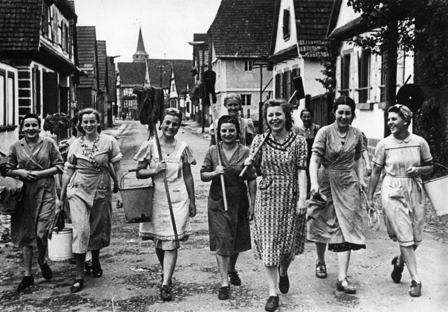 A volunteer squad of the National Socialist Women walks through the street in a small town in the Saar Palatinate in July 1940. This organization for adult German women flourished during the early years of the Third Reich. 