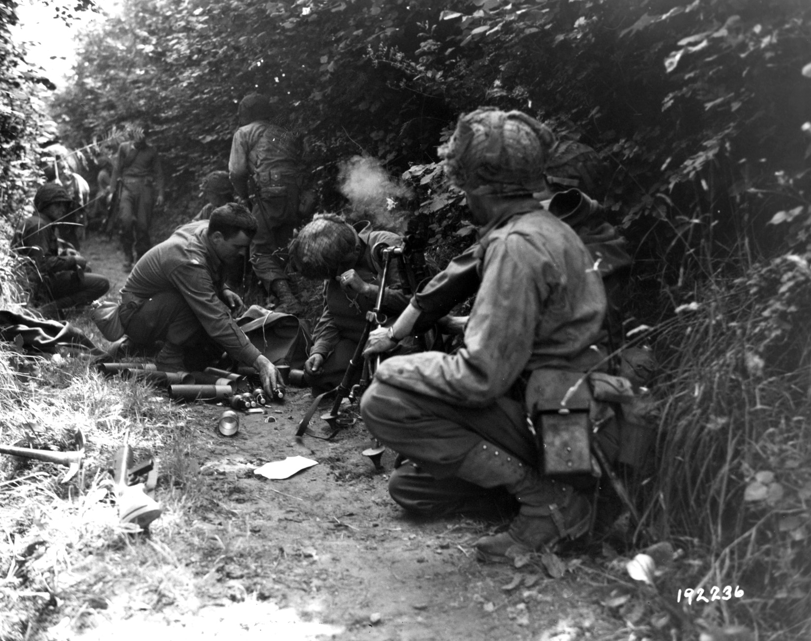 In the shadow of a Normandy hedgerow, American troops lob 81mm mortar shells at the nearby enemy. 