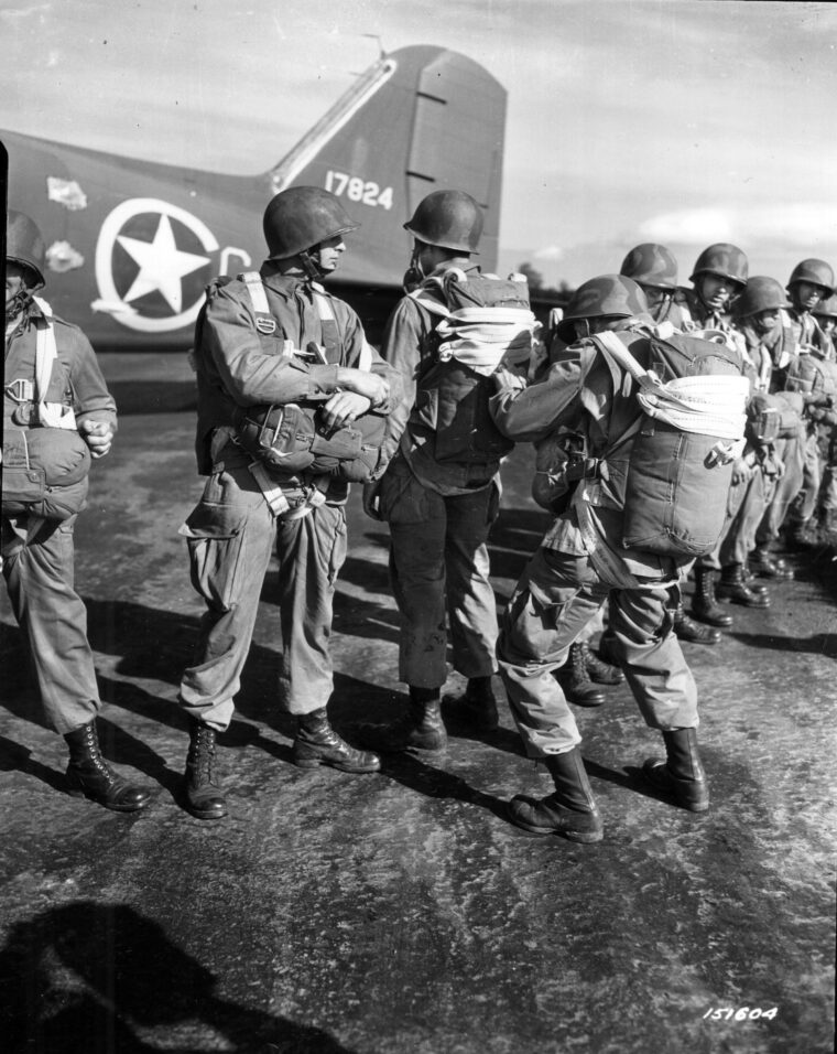 Paratroopers of the 509th Parachute Infantry Regiment (PIR) check main static lines and parachutes before a practice jump in England in October 1942. A month later, these troops executed the first U.S. airborne drop in wartime as a component of Operation Torch.