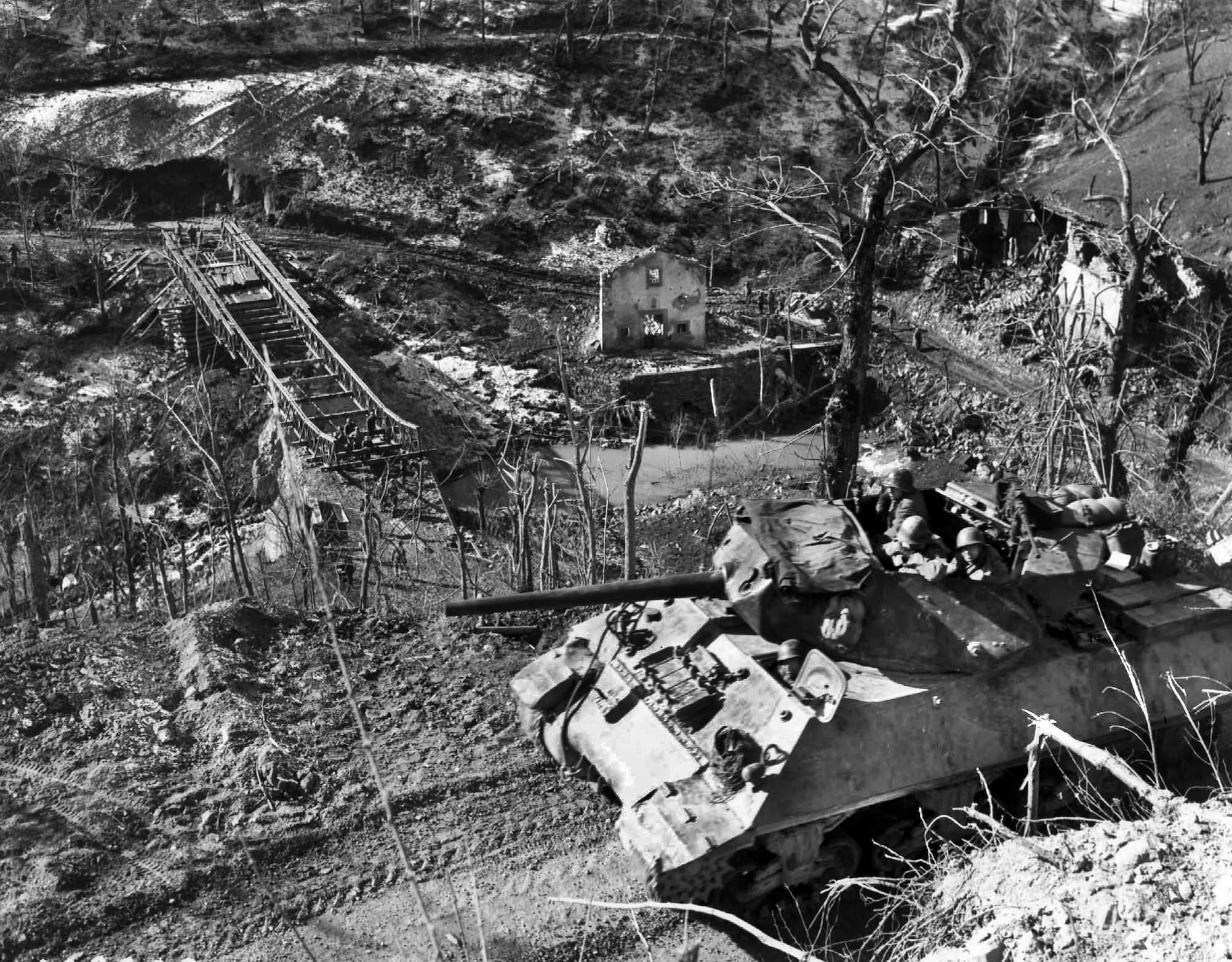 An M-10 Wolverine tank destroyer of the U.S. 701st Tank Destroyer Battalion proceeds cautiously along a narrow road in Italy. The 701st, and other armored units from the 1st Armored Division, supported the effort to capture Mount Porchia with suppressing fire against German gun emplacements on the high ground.