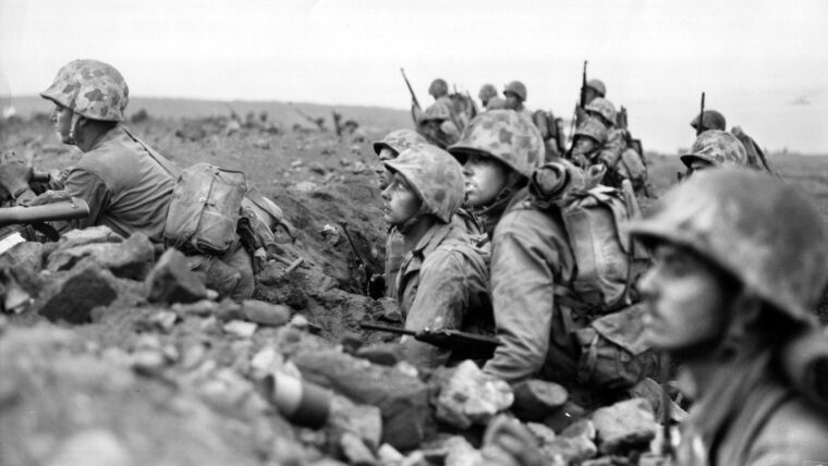 Five hundred yards inland from the invasion beaches at Iwo Jima, Marines of General Clifton B. Cates’ 4th Division await orders to advance on Motoyama Airfield No. 1, one of three airstrips on the island that would facilitate the return of damaged B-29 heavy bombers en route to bases in the Marianas after attacking Japan.