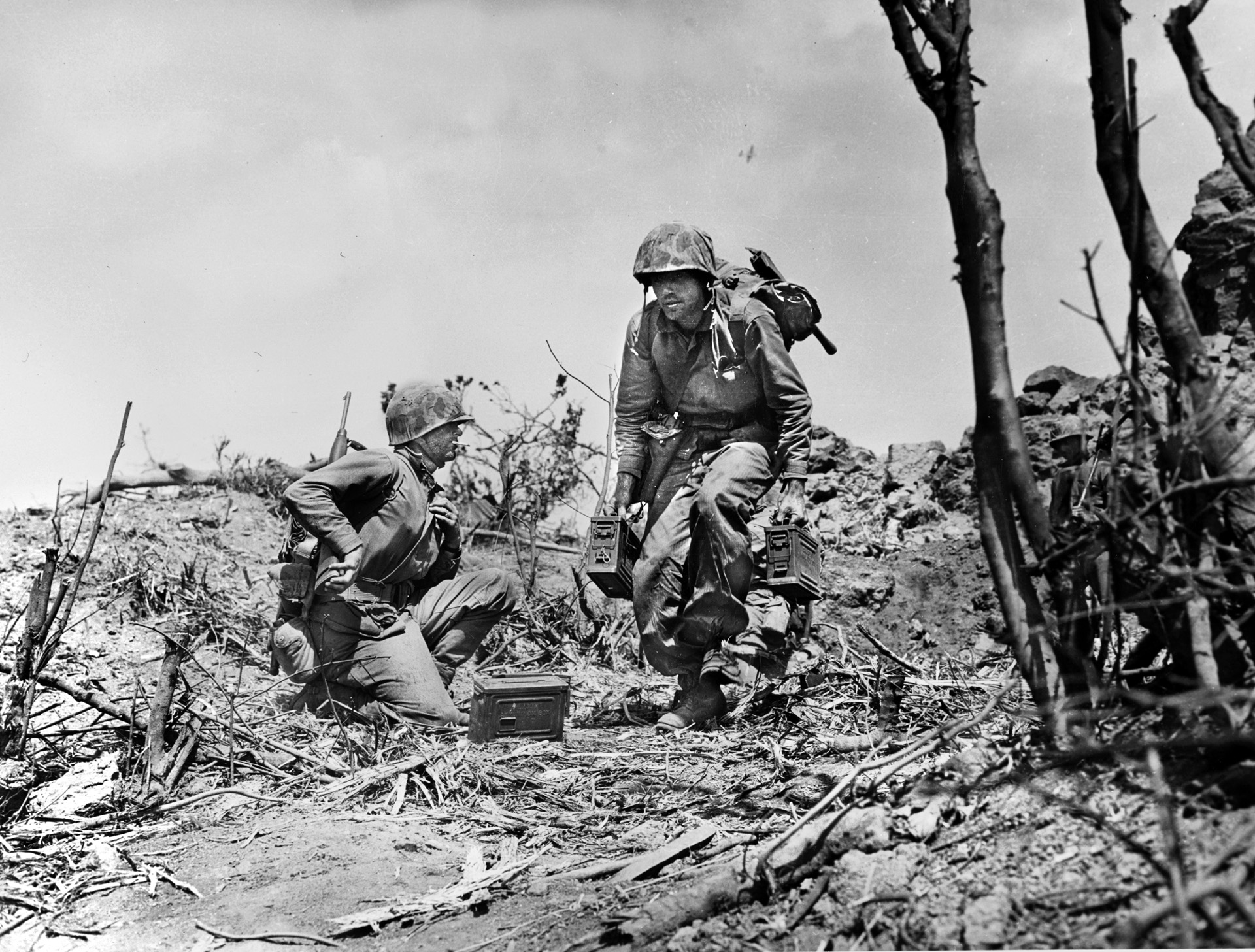 A Marine crouches as he carries ammunition to a position in the thick of the fighting at Hill 362 in the northern area of Iwo Jima.