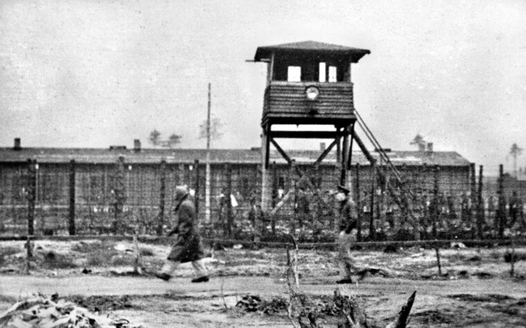 Beneath the watchful eyes of Nazi prison guards, Allied prisoners walk near the perimeter of Stalag Luft III.  Ash spent long hours in solitary confinement there.