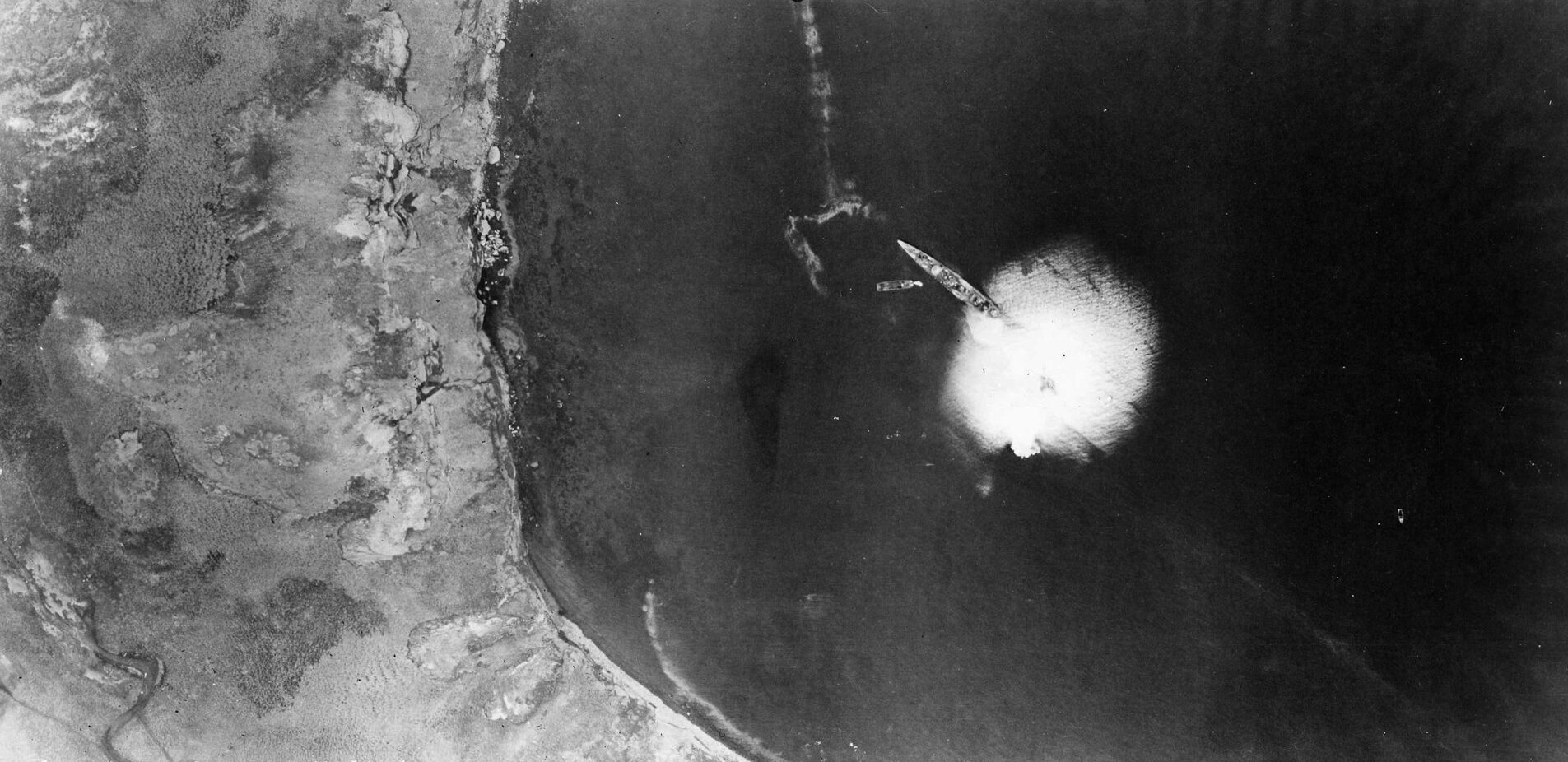 A bomb explodes near a Japanese ship anchored at Kiska. The Americans put heavy pressure on Japanese forces at Kiska and Attu with regular bombing runs.