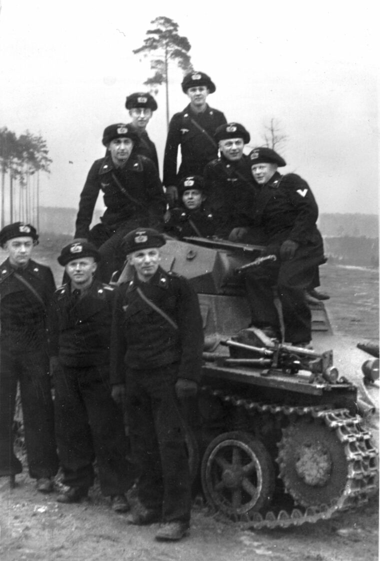 Members of Karl’s panzer platoon pose in their black uniforms at Bamberg Army Base atop a PzKpfw I (armored fighting vehicle Mark I) with twin turret-mounted machine guns, a tank used primarily for training.