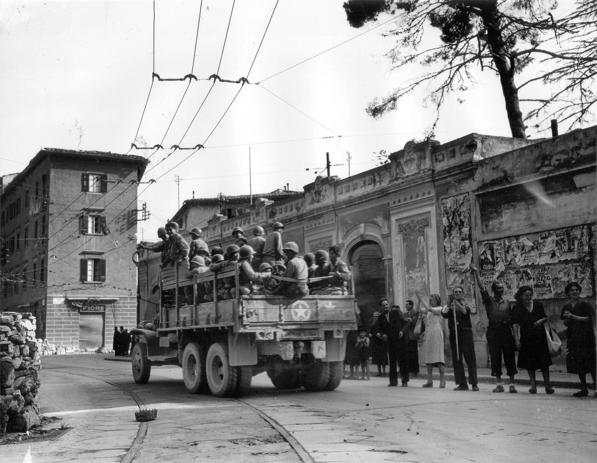 Despite suffering discrimination at home, Nisei troops were often welcomed as liberators in Europe. Here civilians wave to soldiers of the 100th Infantry Battalion as they arrive in Livorno, July 19, 1944. 