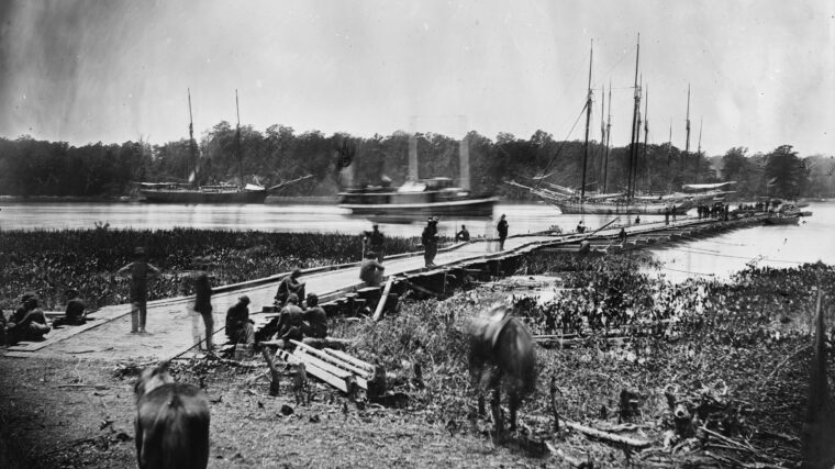 Timothy O’Sullivan photographed the massive Union pontoon bridge over the James River at Weyanoke Point. Anchoring schooners can be seen in the background.