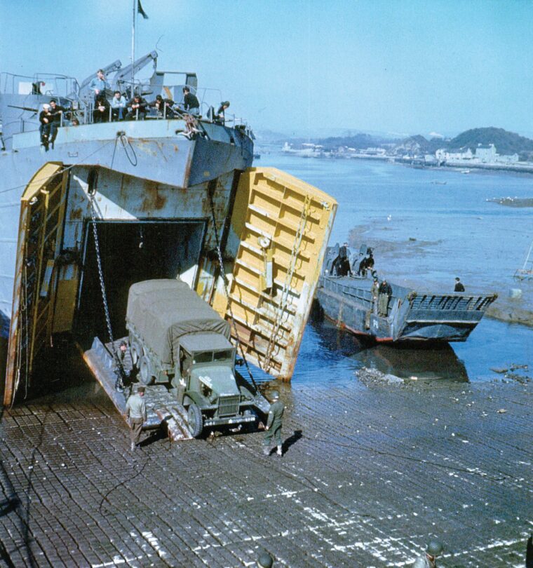 A 4th Infantry Division 2½-ton truck backs onto an LST at Berth Port. An LCM sits to its left.