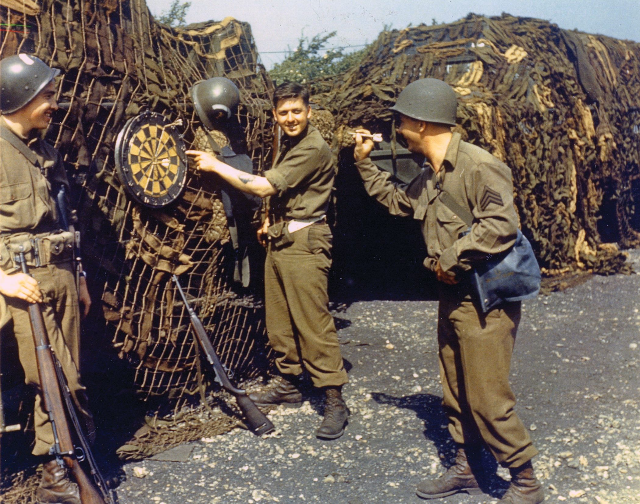 Navy beach masters take a break from their training with a friendly game of darts. The black bag on the shooter’s hip holds a gas mask, attesting to the anxiety of a gas attack so close to the invasion. 