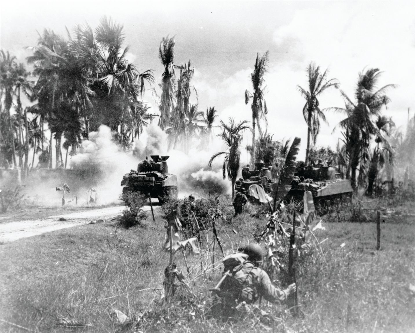 In a photo by Lieutenant Robert Fields, killed shortly after this picture was taken, 40th Infantry Division troops take cover behind advancing tanks while moving against Japanese positions after landing on Panay Island, March 18, 1945.
