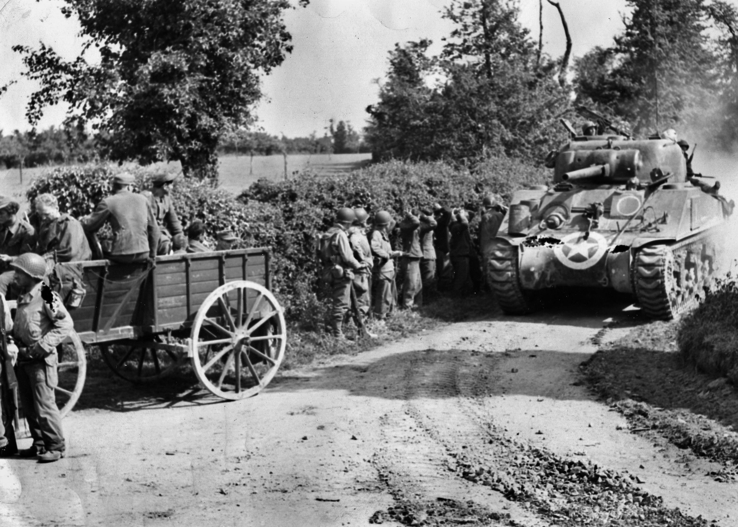 Four days after the invasion, an American M-4A2 Sherman tank moves past groups of Germans who have surrendered to American infantrymen “somewhere in Normandy.”