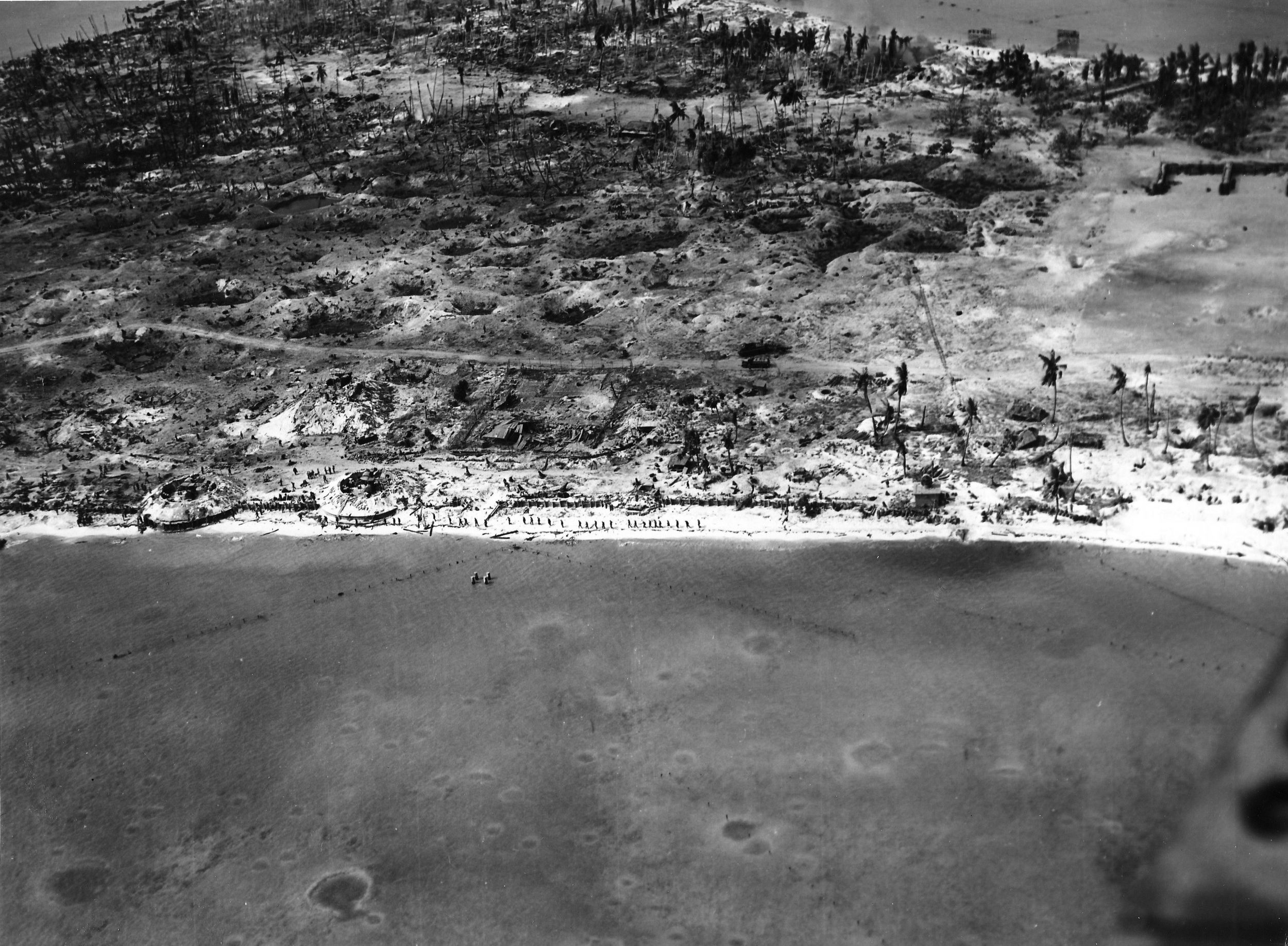 Evidence of the bitter battle for the small spit of land are apparent in this aerial view of Betio, Tarawa Atoll, Gilbert Islands, November 24, 1943, four days after the initial landings. The view is to the north toward “The Pocket”—the last place of Japanese resistance. Two 12.7cm antiaircraft guns are visible at lower left. 