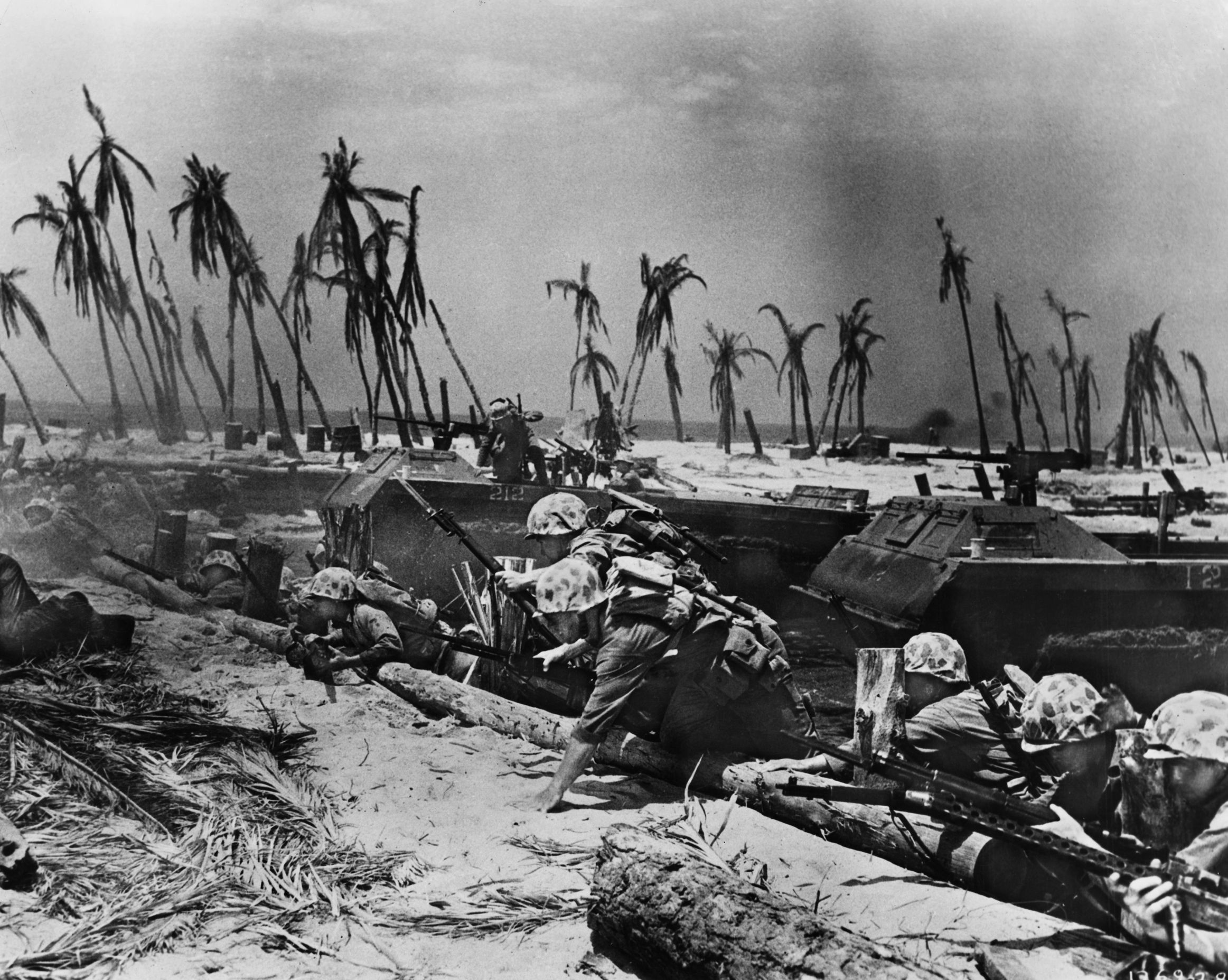 Looking like actors in a Hollywood war film, U.S. Marines climb a log seawall along one of the three Red Beaches at Betio; amphibious tractors (amtracs) are visible behind them. The fight for Tarawa Atoll, November 20-23, 1943, cost the Marines dearly; however, valuable lessons were learned for future U.S. amphibious operations.