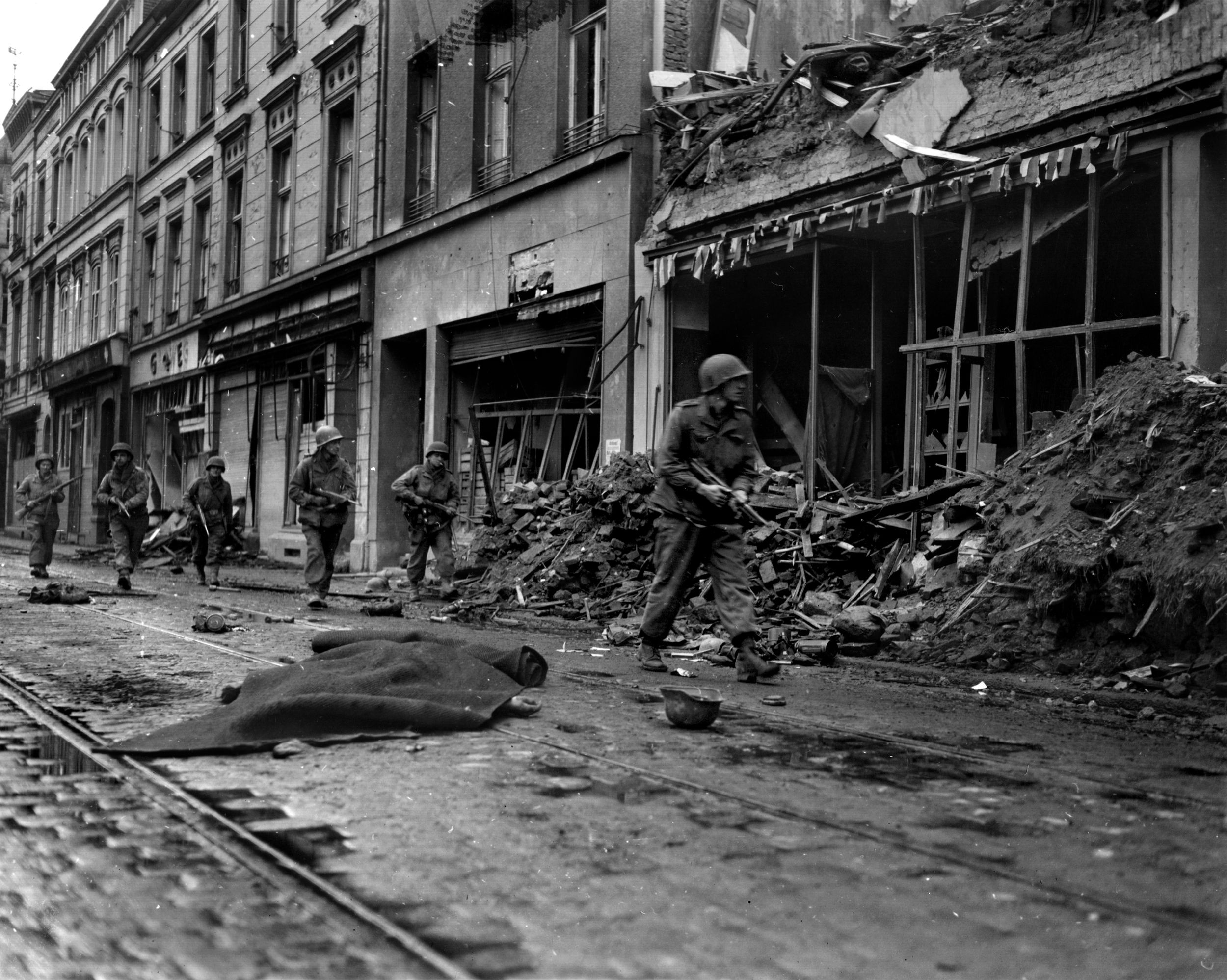 Now bloodied and thoroughly battle-tested, wary 1st Division members advance through the rubble of Bonn, Germany, on March 9, 1945. 