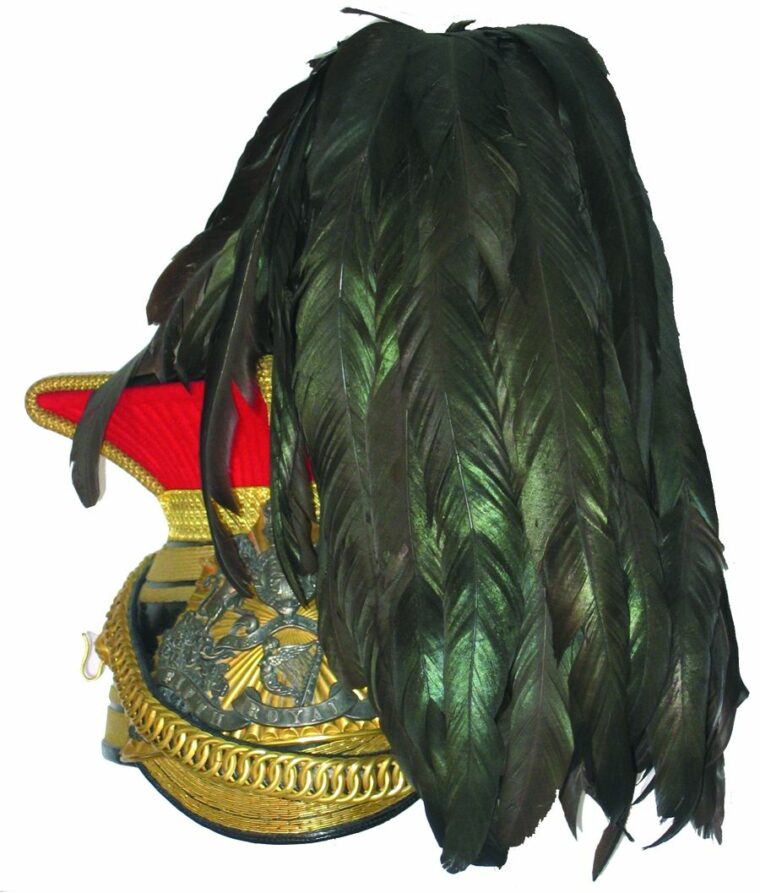 A Lancer cap of the 5th Royal Irish Lancers has a harp surrounded by shamrock sprays and a scroll inscribed “FIFTH ROYAL IRISH” on the helmet plate. 