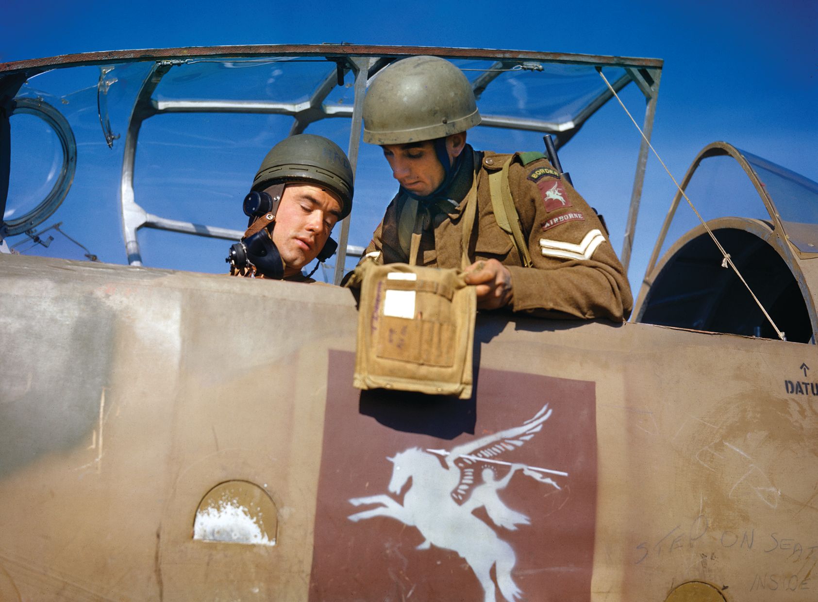 The Pegasus insignia of the 6th Airborne Division prominently emblazoned on the fuselage of their Hotspur glider, a pair of glidermen prepare for a mission. Elements of the 6th Airborne gained fame in the predawn hours of D-Day, capturing the Caen Canal Bridge, which was later renamed Pegasus Bridge in honor of the exploit.