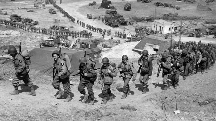 Soldiers of the U.S. Army’s 2nd Division file ashore from Omaha Beach several days after the D-Day landings in Normandy. During the course of World War II, the Army and Marine Corps changed the configuration of their combat divisions to make them more efficient.