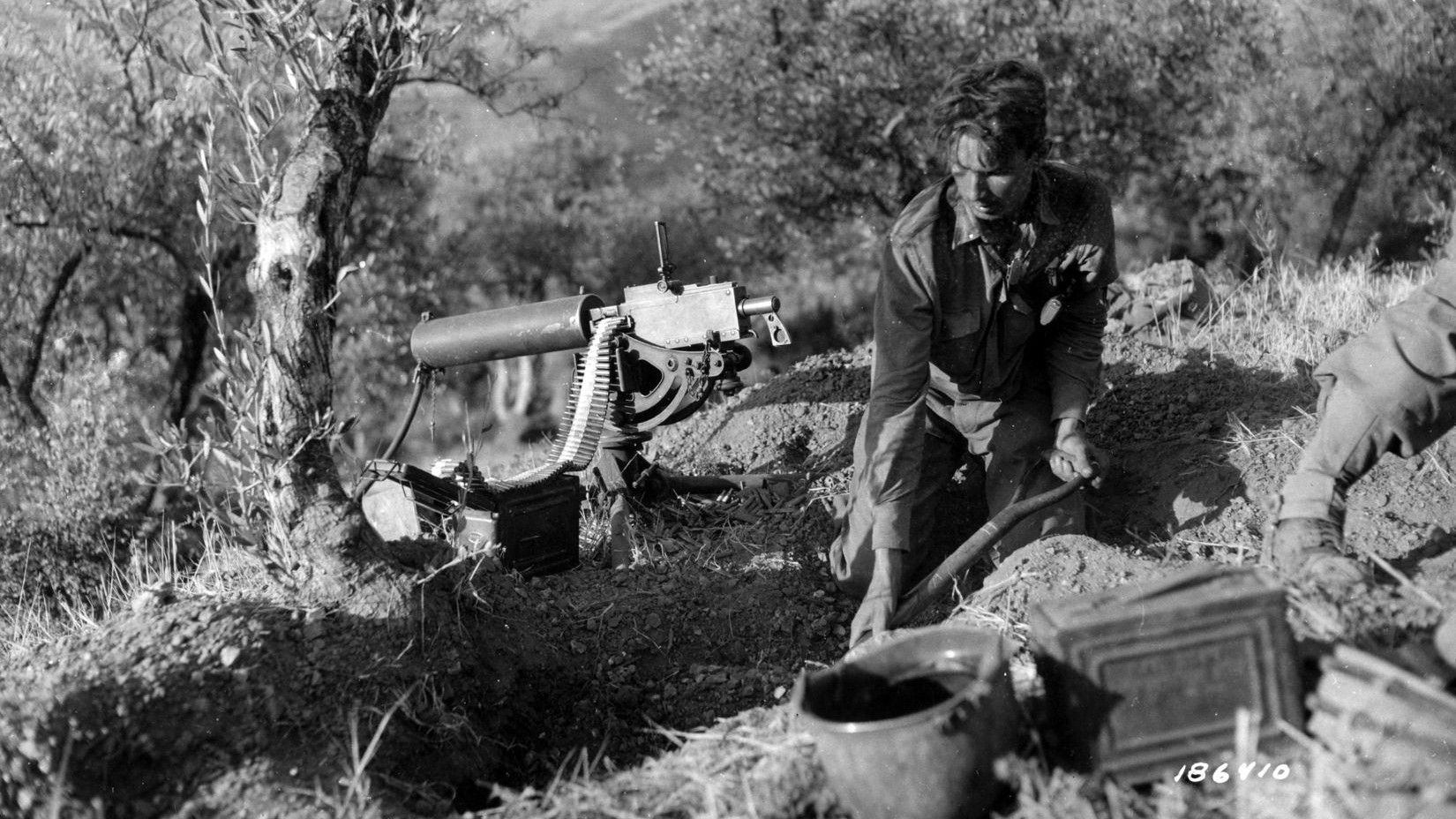 On August 11, 1943, an American soldier digs in with his heavy machine gun on a hillside near Brolo. U.S. forces attempted to outflank German troops with an amphibious landing near this site during Operation Husky.
