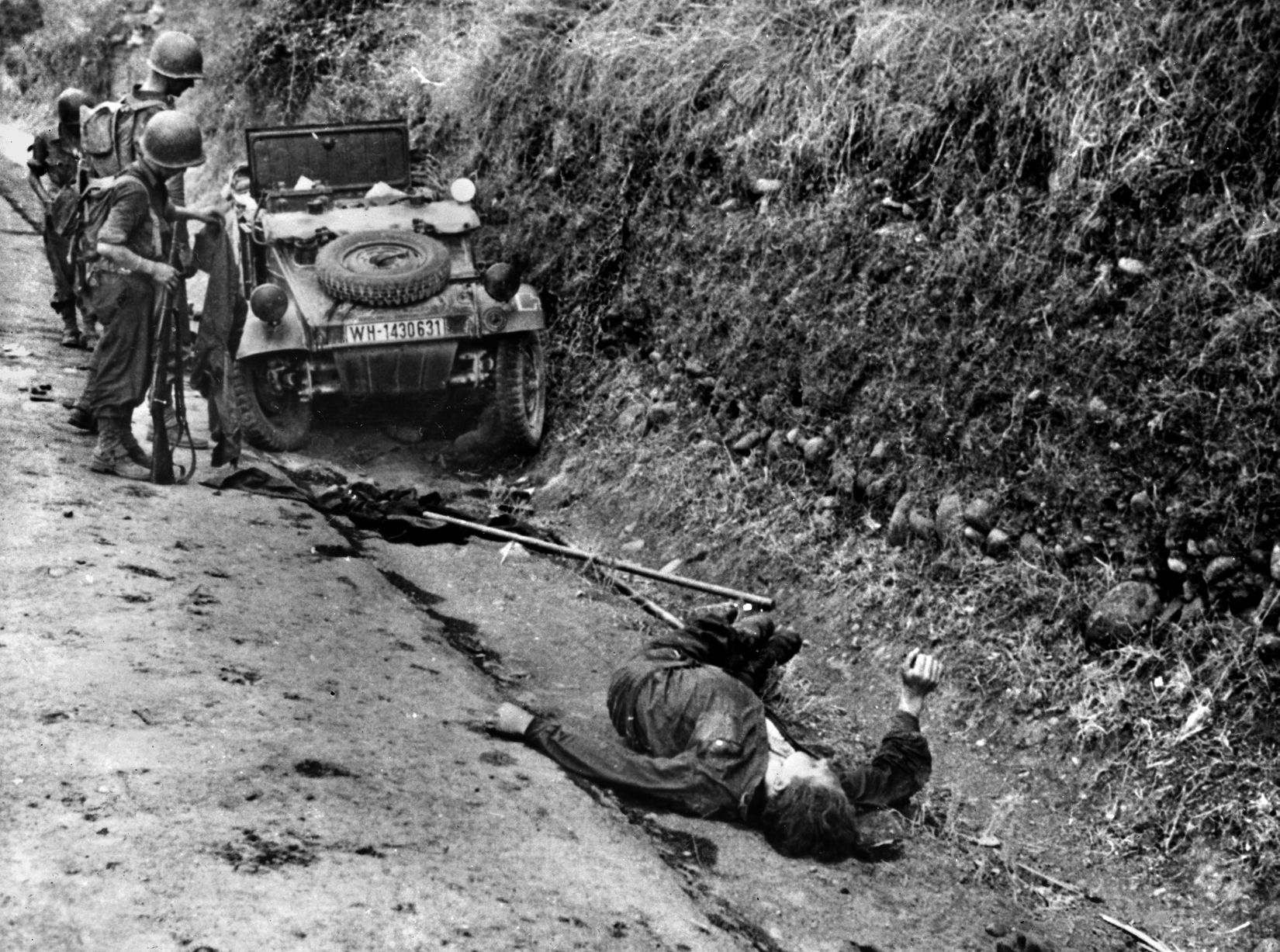 Two American soldiers inspect the wreckage of a German car as its former occupant lies dead in the road a few feet away. The fighting on Sicily was brutal, but thousands of Axis troops managed to escape to the Italian mainland.