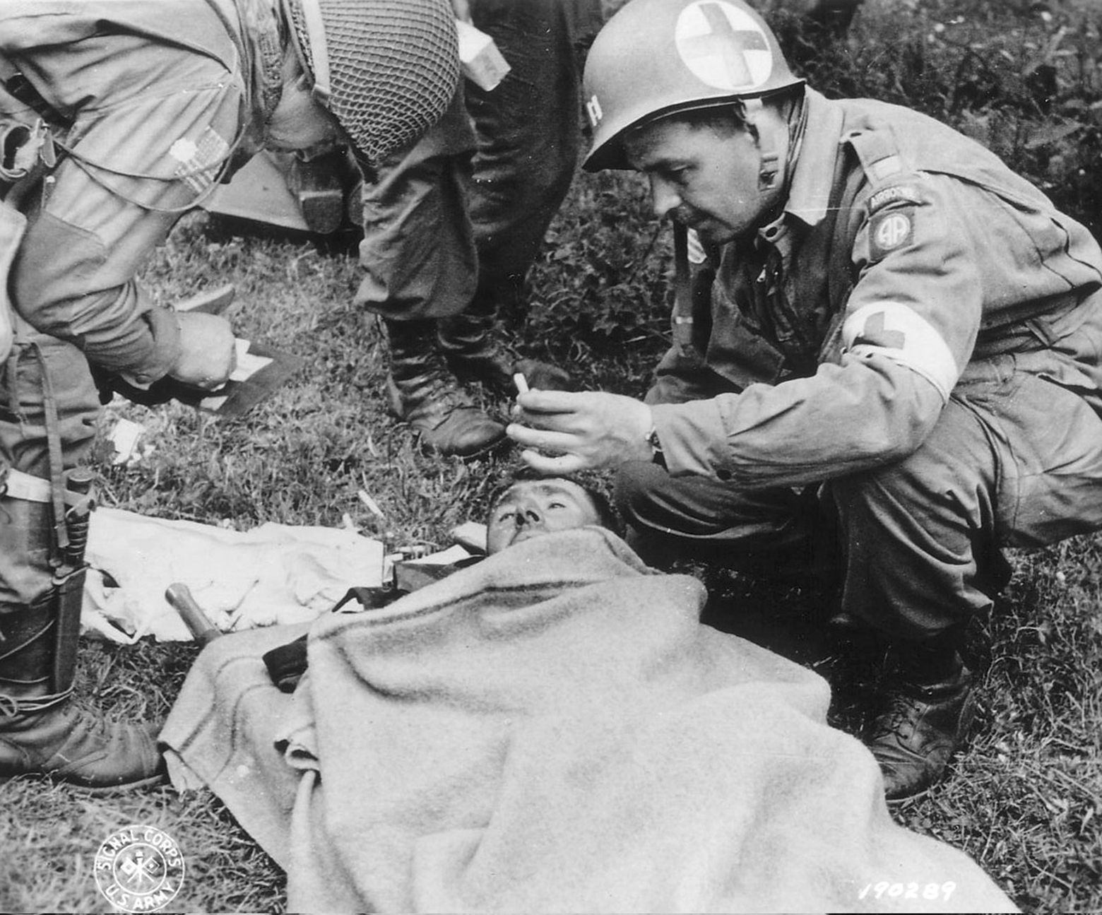 A captain in an 82nd Airborne Division medical unit (right) gives a cigarette to a wounded German soldier.